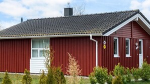 A red building with a dark roof, a chimney, and a small window. - Holiday Home in GrÃ¶mmitz (Groemitz)