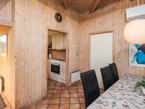 Interior de madera con cocina, comedor y una puerta.