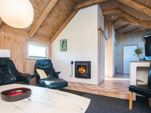 Una sala de estar acogedora con chimenea, muebles de cuero y vigas de madera en el techo.