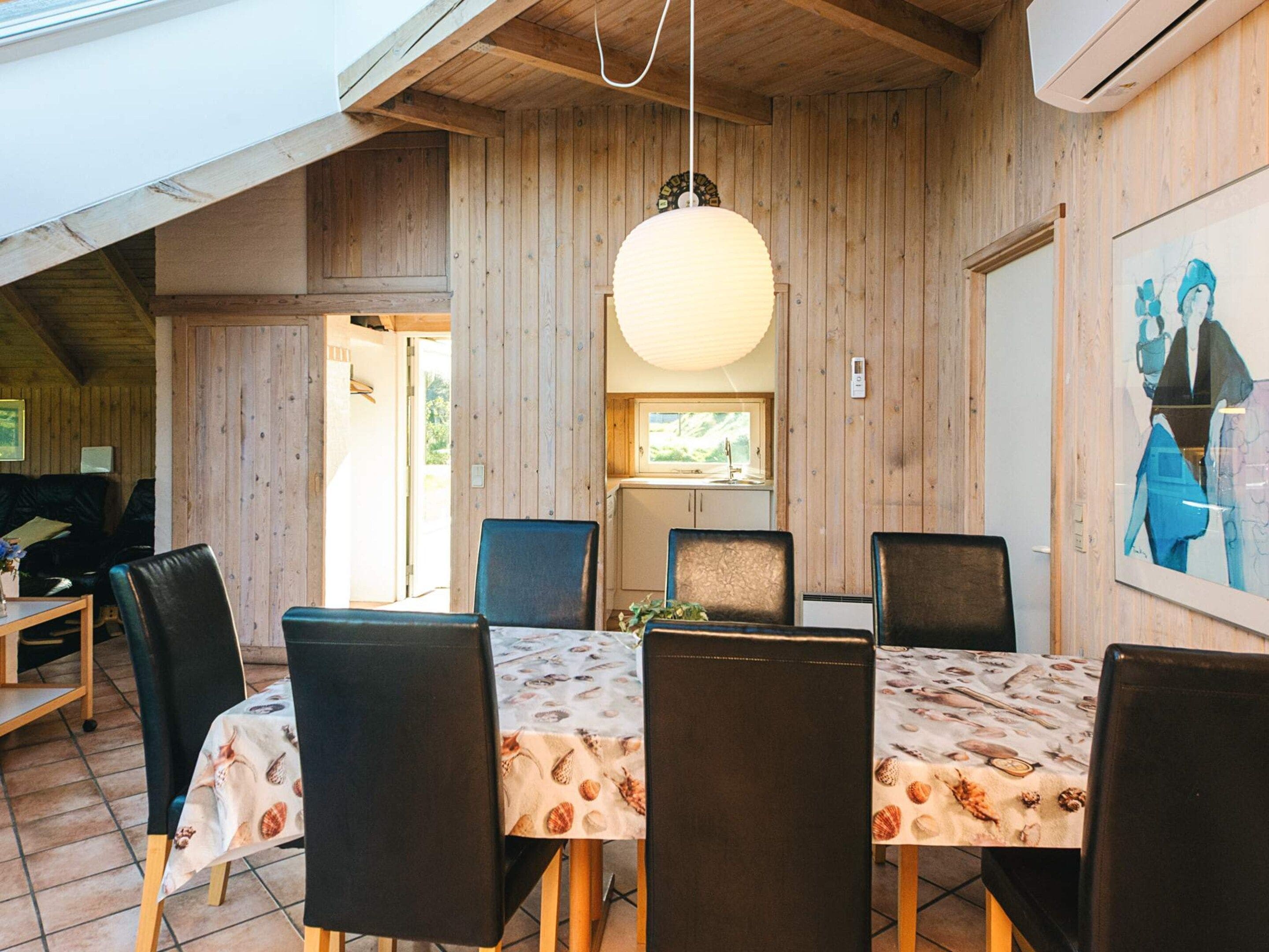 A dining area with a round table, chairs, and a hanging light fixture.