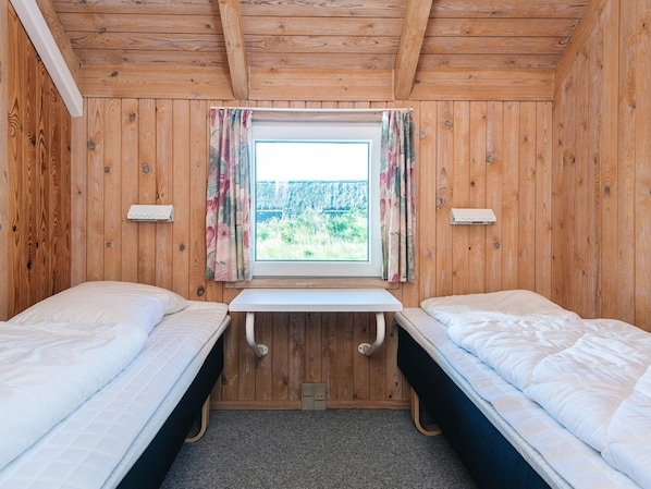 A room with wooden walls and a window with curtains. There are two beds with white bedding. - 4 Star Holiday Home in Vejers Strand (Vejers Strand)