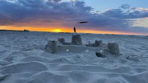 Une plage de sable où se trouve une personne, près d’une structure faite de blocs de béton.