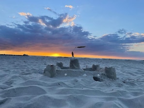 Una playa arenosa con una persona de pie cerca de una estructura hecha con bloques de hormigón.
