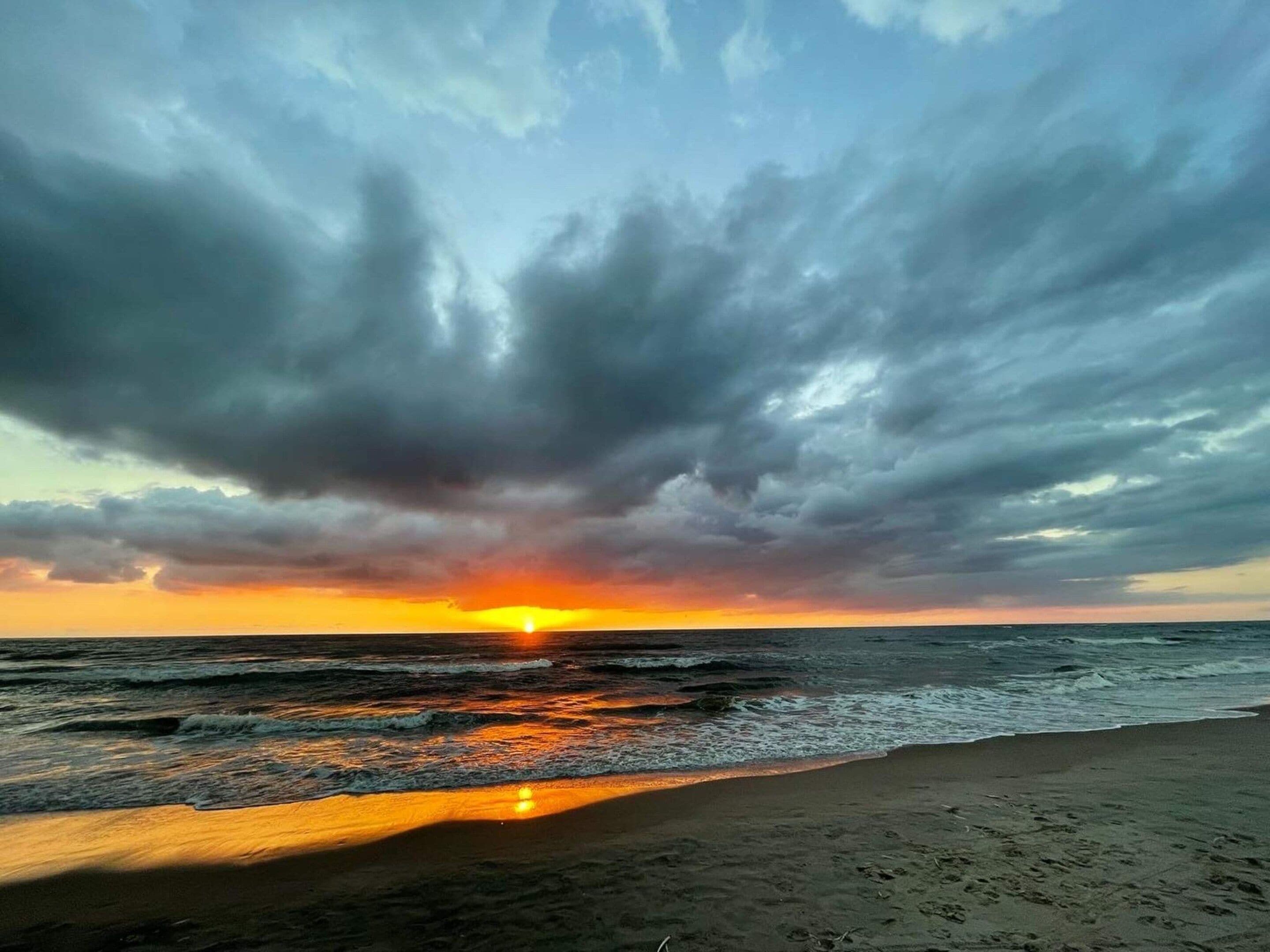 A beach with waves and a sunset.