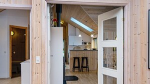Ein offenes DurchgangsbereIch zu einer Küche mit Holzwänden, einer sichtbaren Decke und einer Bar mit Hockern.