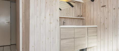 A modern bathroom with wooden walls, a white countertop, and a built-in sink.