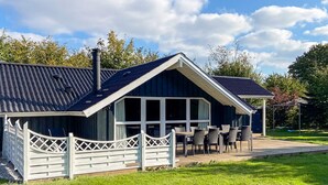 A modern house with a sloped roof, large windows, and a fenced patio area with outdoor furniture. - 4 Star Holiday Home in Sydals (Sydals)