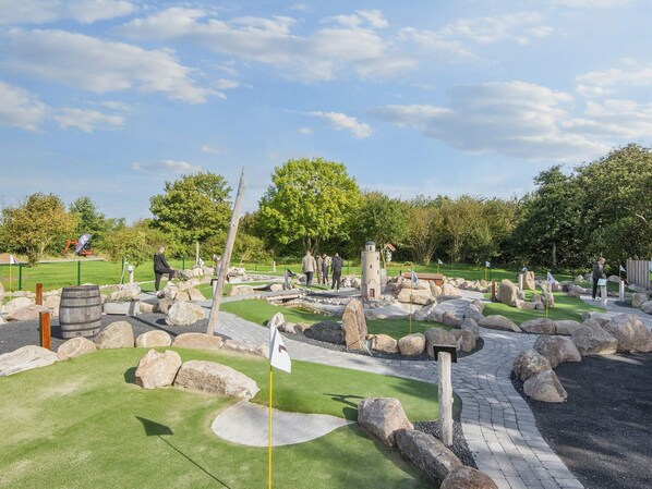 Un campo de mini golf con diversos obstáculos y una bandera en el hoyo 7.