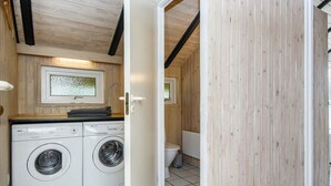 Un espace buanderie compact comprenant un lave-linge, un sèche-linge, des toilettes et une fenêtre donnant sur un paysage agréable.