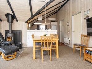 Una sala de estar acogedora con chimenea, comedor y cocina al fondo.