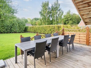 An outdoor deck with a dining table and chairs, surrounded by a wooden fence and a well-maintained lawn. - 4 Star Holiday Home in Sydals (Sydals)