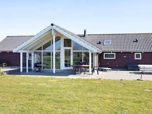 A house with a covered patio area, large windows, and a tiled roof.