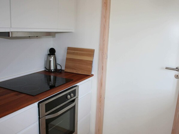 A kitchen with a stovetop, oven, and a coffee maker. - 6 Person Holiday Home in Gudhjem (Gudhjem)