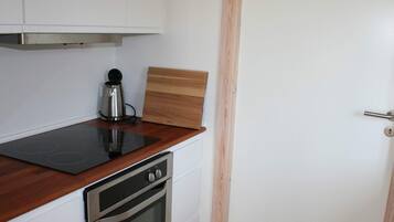 Una cocina con estufa, horno y cafetera.
