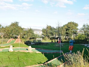 A miniature golf course with a green lawn, sand traps, and a wooden bench. - 4 Person Holiday Home in Fano (Fano)