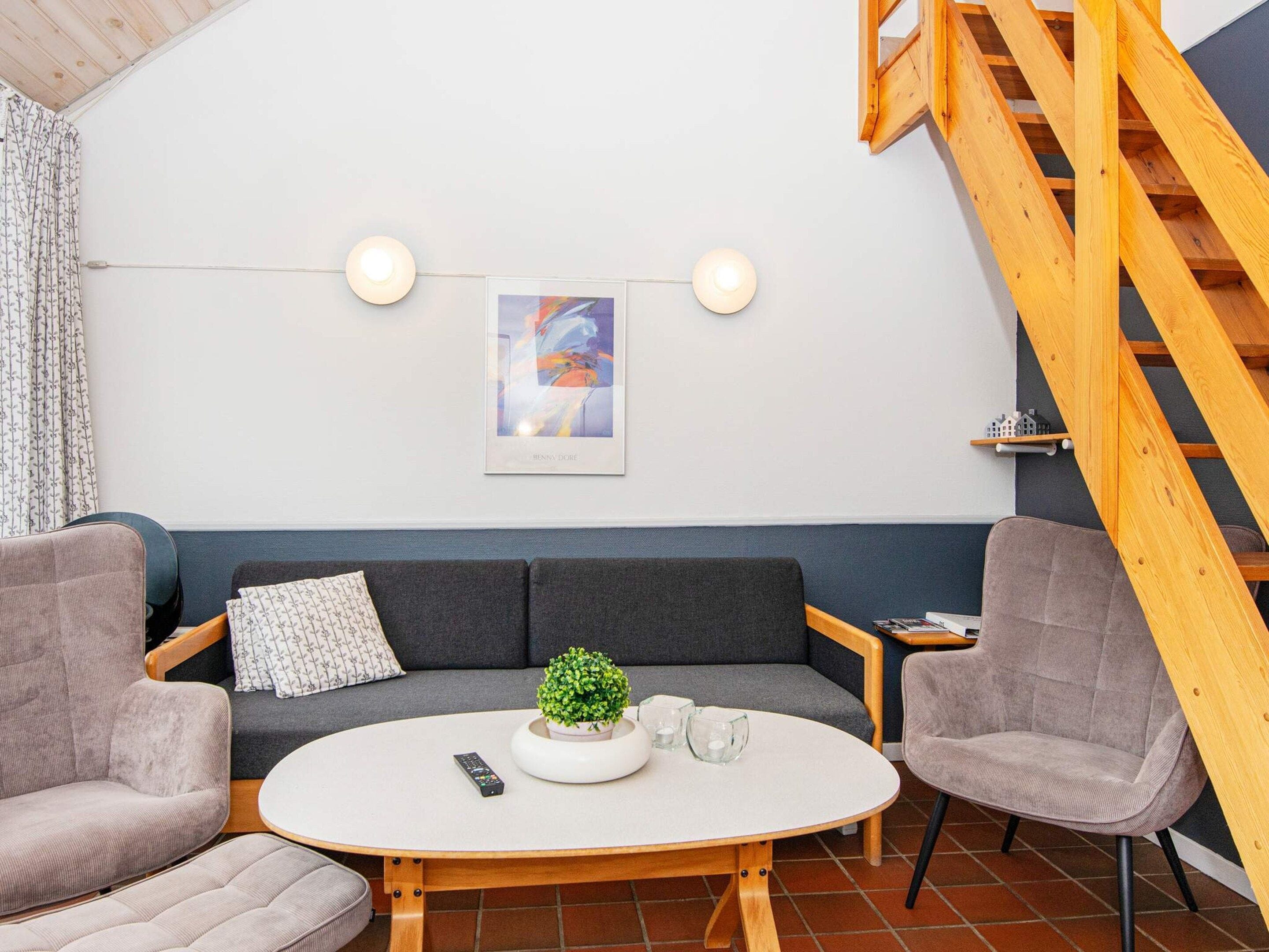 A cozy living area with a sofa, two armchairs, a coffee table, and a staircase.