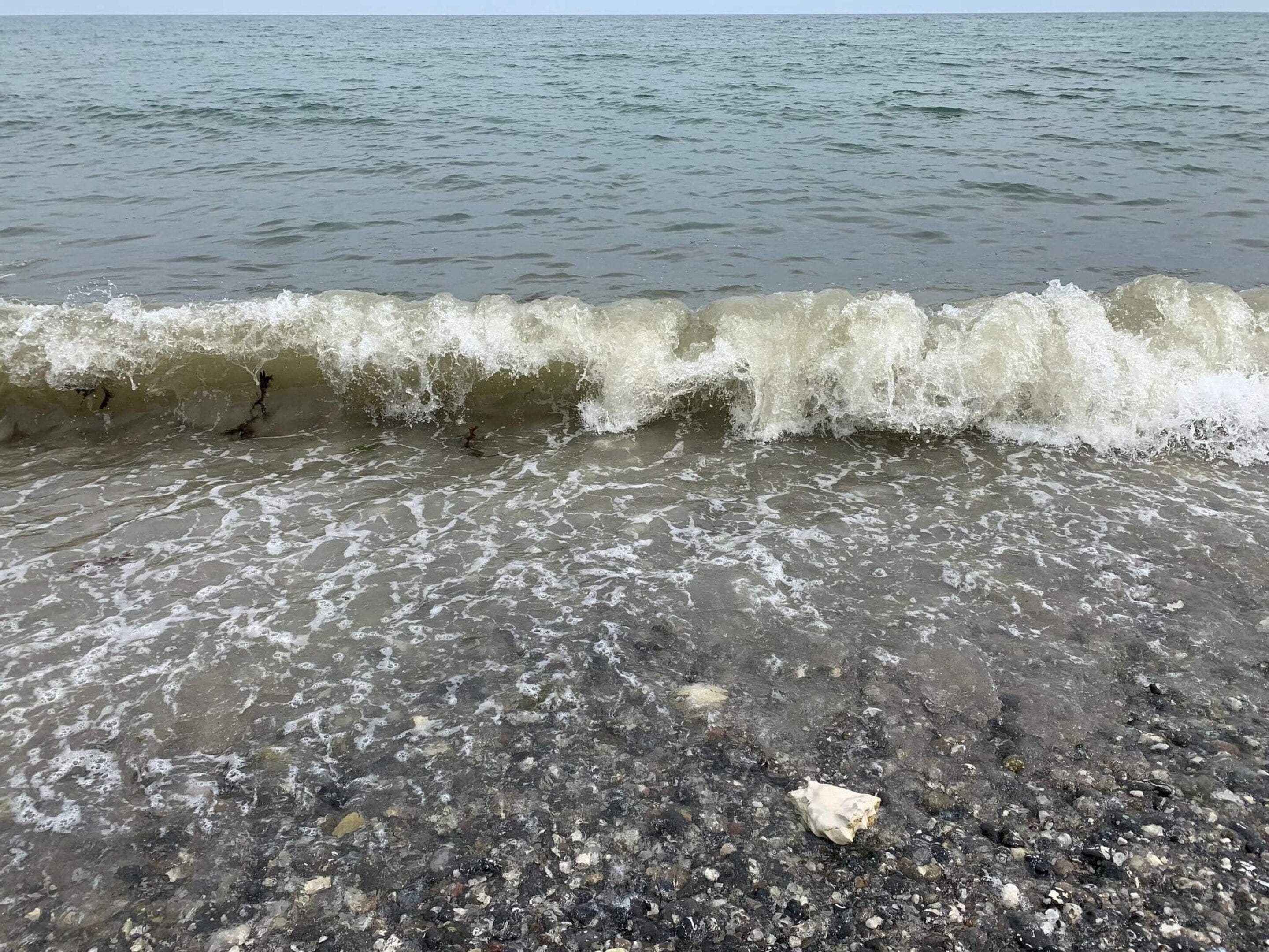 A beach with waves crashing onto a pebbly shore.