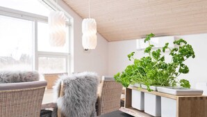A modern dining area with wicker chairs, a black countertop, and a wooden shelf with fresh herbs. - 6 Person Holiday Home in Brovst (Brovst)