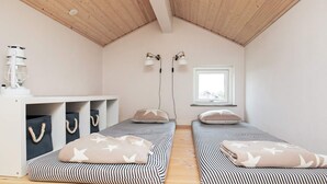 A small, cozy room with two beds, a desk, and a window. - 6 Person Holiday Home in Brovst (Brovst)