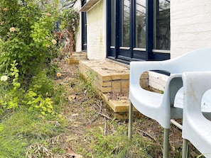 A garden area with steps leading to a building, a white plastic chair, and a bush with flowers. - 11 Person Holiday Home in Hurup Thy (Hurup Thy)