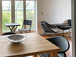 Un comedor con mesa de madera, dos sillas y un ventanal con vistas a la vegetación.