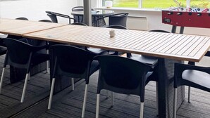 A room with a long wooden table, black chairs, a window with a view of greenery, and a foosball table. - Scenic Retreat in Boddum (Hurup Thy)