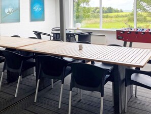 A room with a long wooden table, black chairs, a window with a view of greenery, and a foosball table. - 11 Person Holiday Home in Hurup Thy (Hurup Thy)