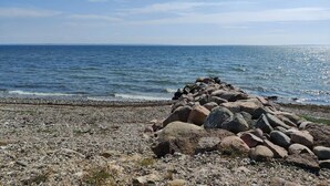 A rocky shoreline with a clear view of the sea and a distant horizon. - Scenic Retreat in Boddum (Hurup Thy)