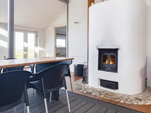 A room with a stone fireplace, a wooden table, and black chairs. - 11 Person Holiday Home in Hurup Thy (Hurup Thy)