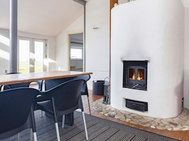 Una habitación con chimenea de piedra, una mesa de madera y sillas negras.