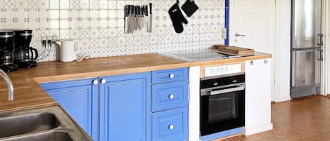 A kitchen with a blue island, stainless steel appliances, and patterned backsplash.