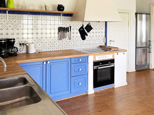 Una cocina con una isla azul, electrodomésticos de acero inoxidable y salpicadero decorado.
