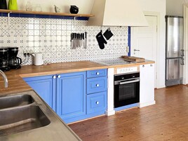 A kitchen with a blue island, stainless steel appliances, and patterned backsplash.