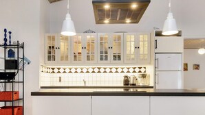A modern kitchen with white cabinets, a black countertop, and pendant lighting. - Family Retreat: Sauna & Fenced Garden (Rodby)