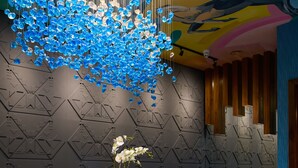 A modern reception area with a marble reception desk, a hanging blue crystal chandelier, and a geometric patterned wall. - Arthaus Hotel (Dublin)