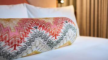 A bed with a patterned pillow and a white sheet.