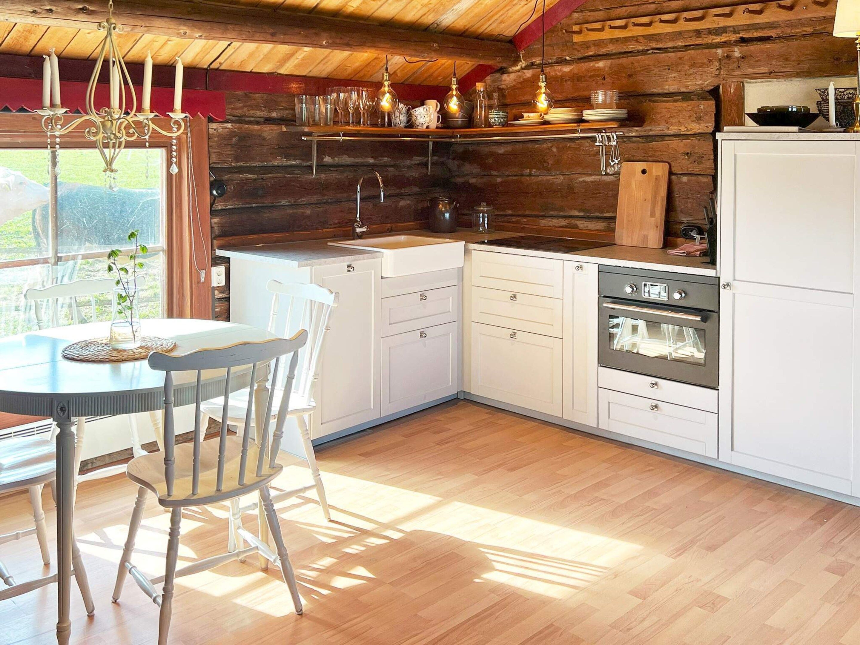 A kitchen with wooden walls, a white countertop, and a dining area with a table and chairs.