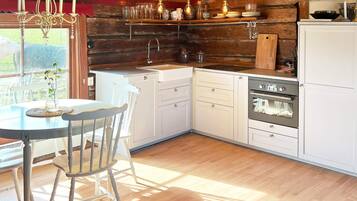 A kitchen with wooden walls, a white countertop, and a dining area with a table and chairs.