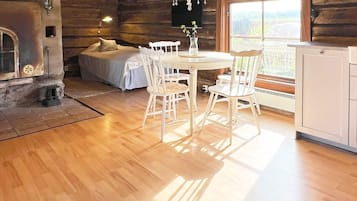 A cozy log cabin interior with a dining area, a bed, and a fireplace.