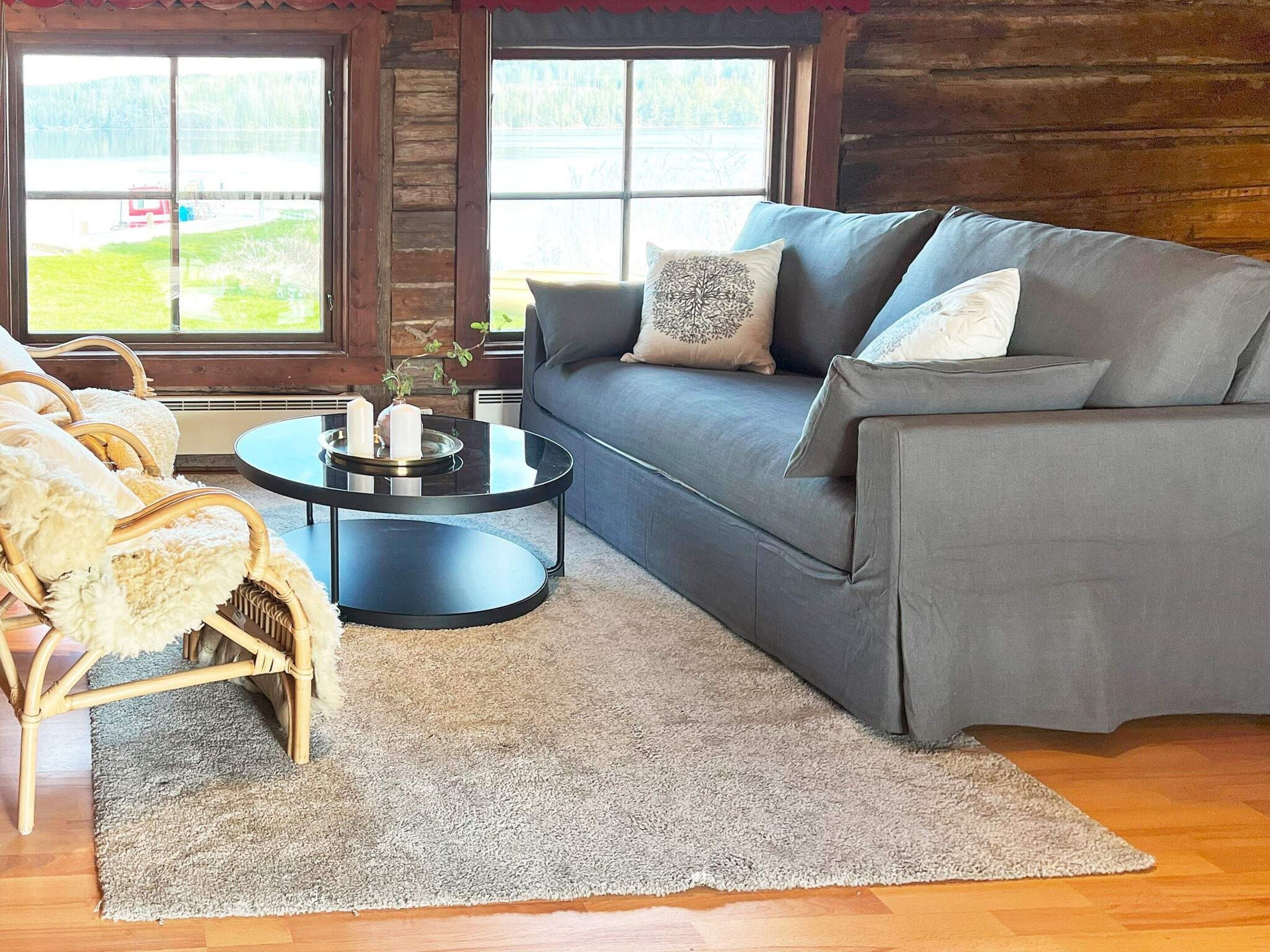 A cozy living room with a grey sofa, a round black coffee table, and a white furry chair.