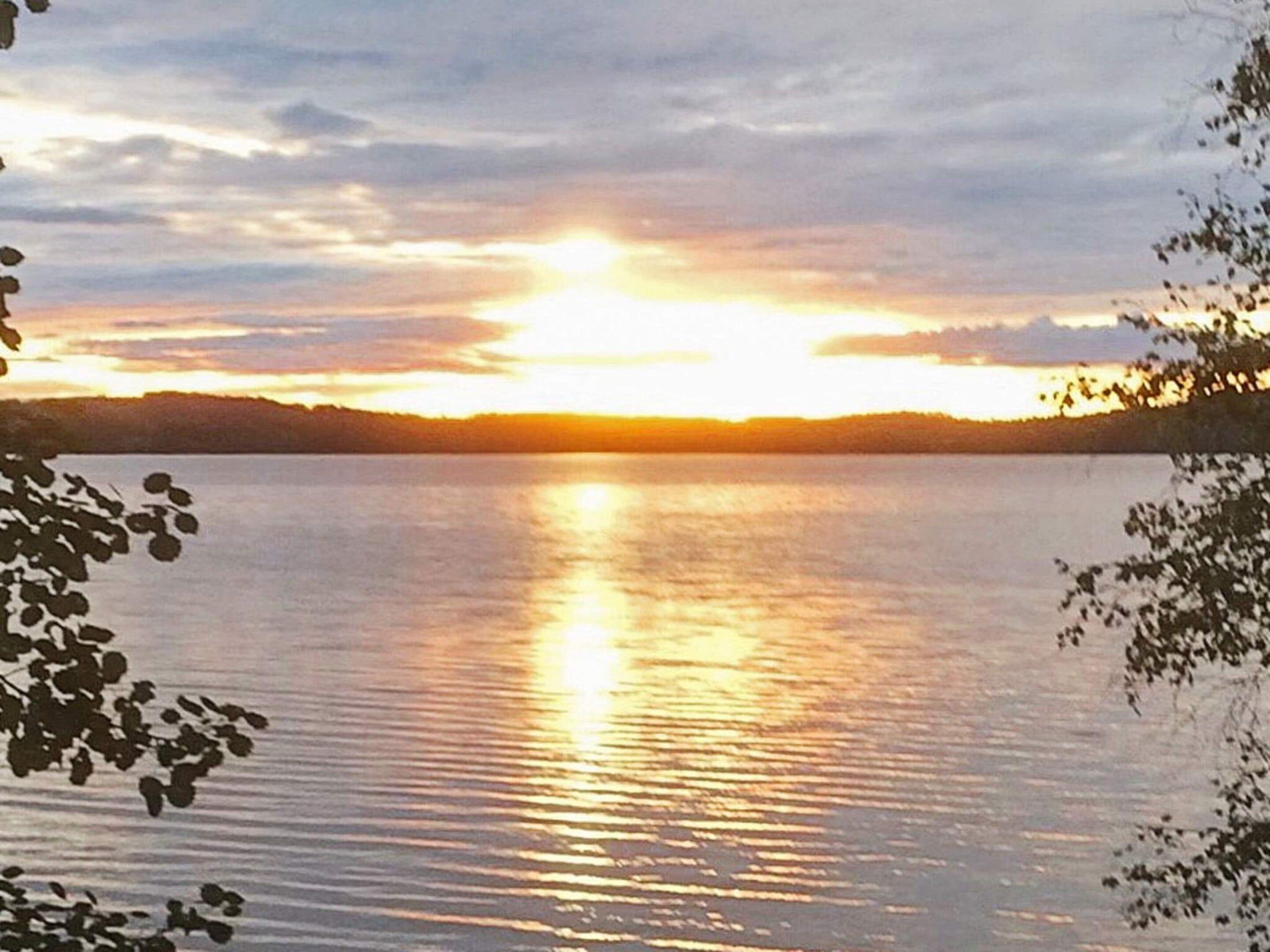 Um lago tranquilo ao pôr do sol, com céu limpo.