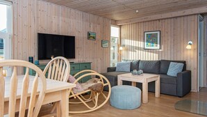 A cozy room with wooden walls, a television, a sofa, a small table, and a rocking chair. - 4 Person Holiday Home in Hejls-by Traum (Hejls)