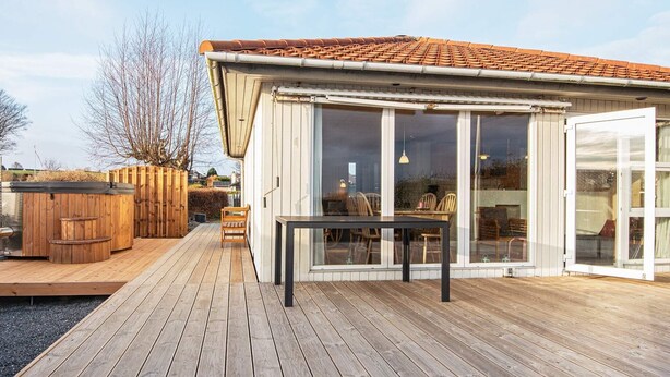 A wooden deck with a hot tub, a table, and chairs. - 4 Person Holiday Home in Hejls-by Traum (Hejls)
