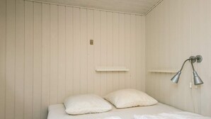 Ein Schlafzimmer mit einem Bett, zwei Kissen, einer weißen Wand und einer Wandleuchte.