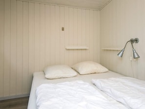 A bedroom with a bed, two pillows, a white wall, and a wall-mounted lamp. - 4 Star Holiday Home in Ebeltoft (Ebeltoft)