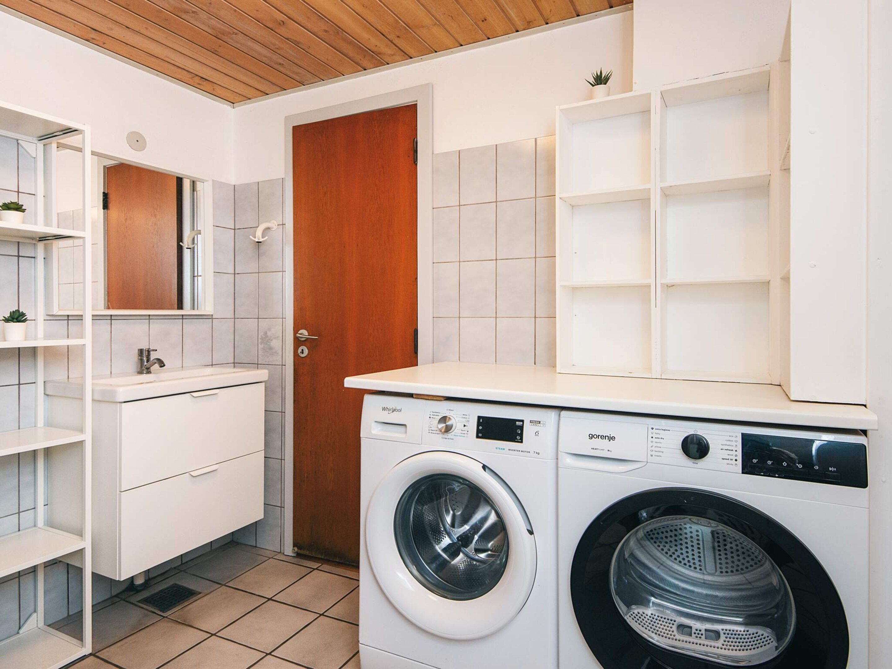 Une petite buanderie équipée d’un lave-linge, d’un sèche-linge et d’une porte en bois.