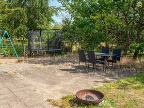 An outdoor seating area with a table and chairs, surrounded by trees. - 4 Star Holiday Home in Ebeltoft (Ebeltoft)