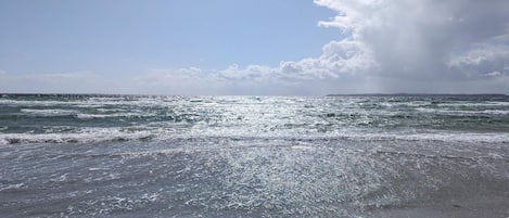 A beach with waves and a cloudy sky.