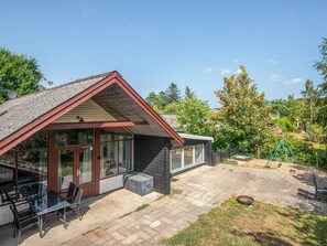A house with a covered patio area, a small outdoor seating area, and a play structure. - 4 Star Holiday Home in Ebeltoft (Ebeltoft)
