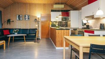 Et moderne køkken med træskabe, en central ø og et spiseområde med bord og stole.